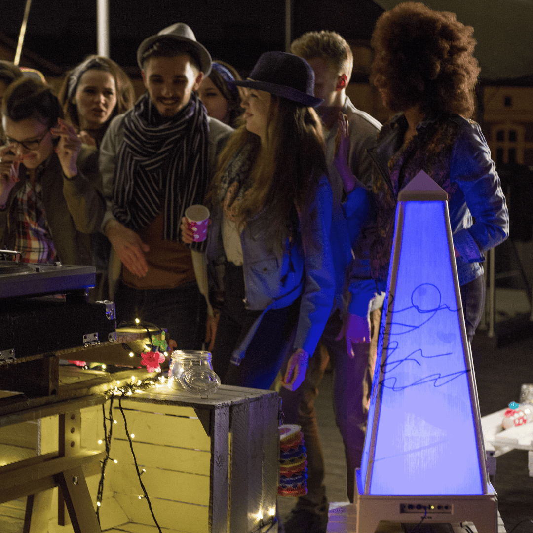 Group of young people enjoying an evening party with music, string lights, and a glowing XOUNTS speaker as the centerpiece.